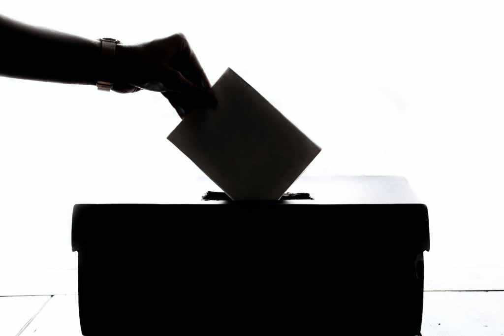 Silueta de una mano que deposita un voto en una urna